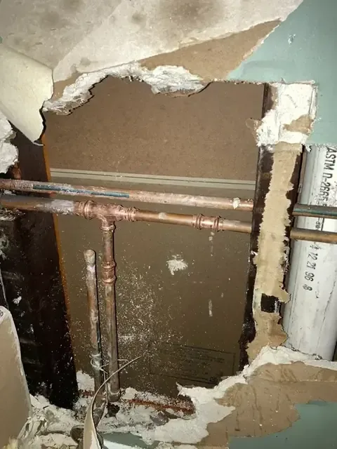 Wall opened at the base to reach leaking copper supply pipes