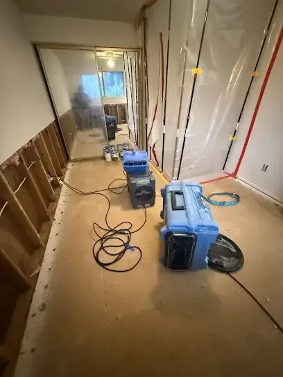 Plastic containment, a dehumidifier and an air scrubber set up to dry a stripped hallway
