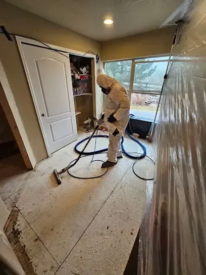 Technician in a protective suit extracting a contaminated floor in a stripped room