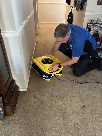 Technician running an extraction wand over standing water on a flooded floor